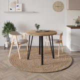 Decortie Dining Table with a round wooden top and sleek black legs in a modern dining room setup