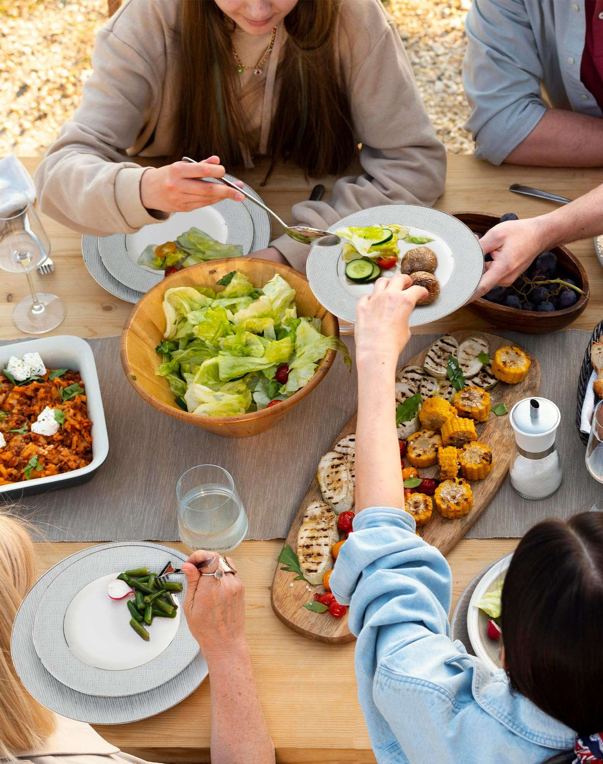 Elegant dinner plates set for a family meal featuring salads and various dishes served outdoors