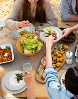 Elegant dinner plates set for a family meal featuring salads and various dishes served outdoors