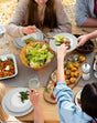 Elegant dinner plates set for a family meal featuring salads and various dishes served outdoors