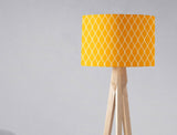 Bright yellow lampshade with a geometric pattern on a wooden tripod lamp
