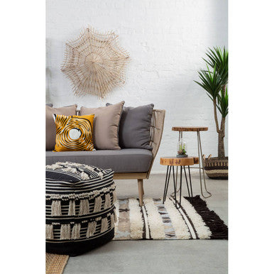 Stylish Embroidered Cushion on a grey sofa, complemented by decorative plants and a unique pouf