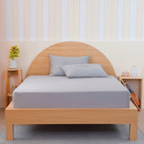 Grey fitted sheet by SHEET STORY on a wooden bed with matching pillows for a modern look