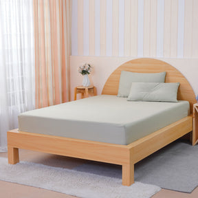 Light green fitted sheet on a wooden bed with soft pillows in a minimalistic bedroom