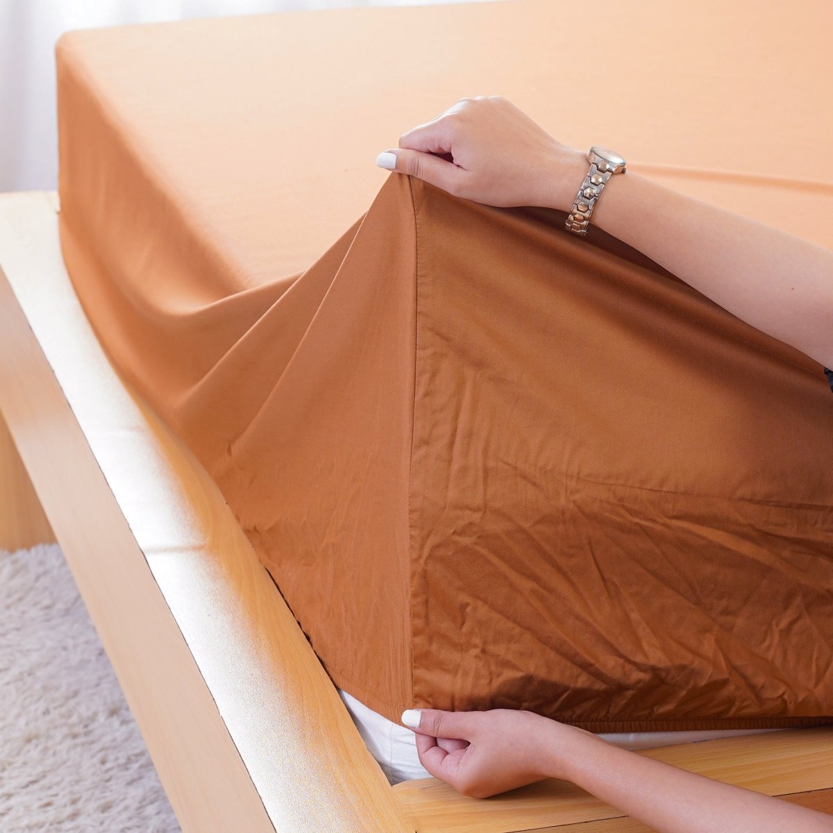 SHEET STORY Fitted Sheet being securely placed on a mattress in warm brown colour