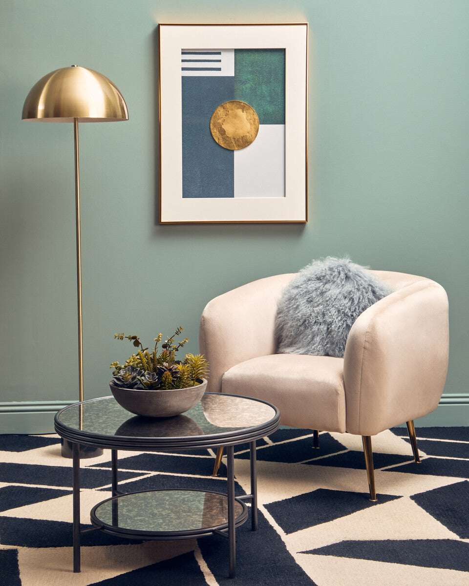 Orsina Floor Lamp in Gold beside a plush armchair and decorative table in stylish living room