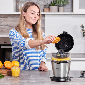 Fridja Citrus Juicer with a woman juicing an orange, ideal for fresh juice enthusiasts