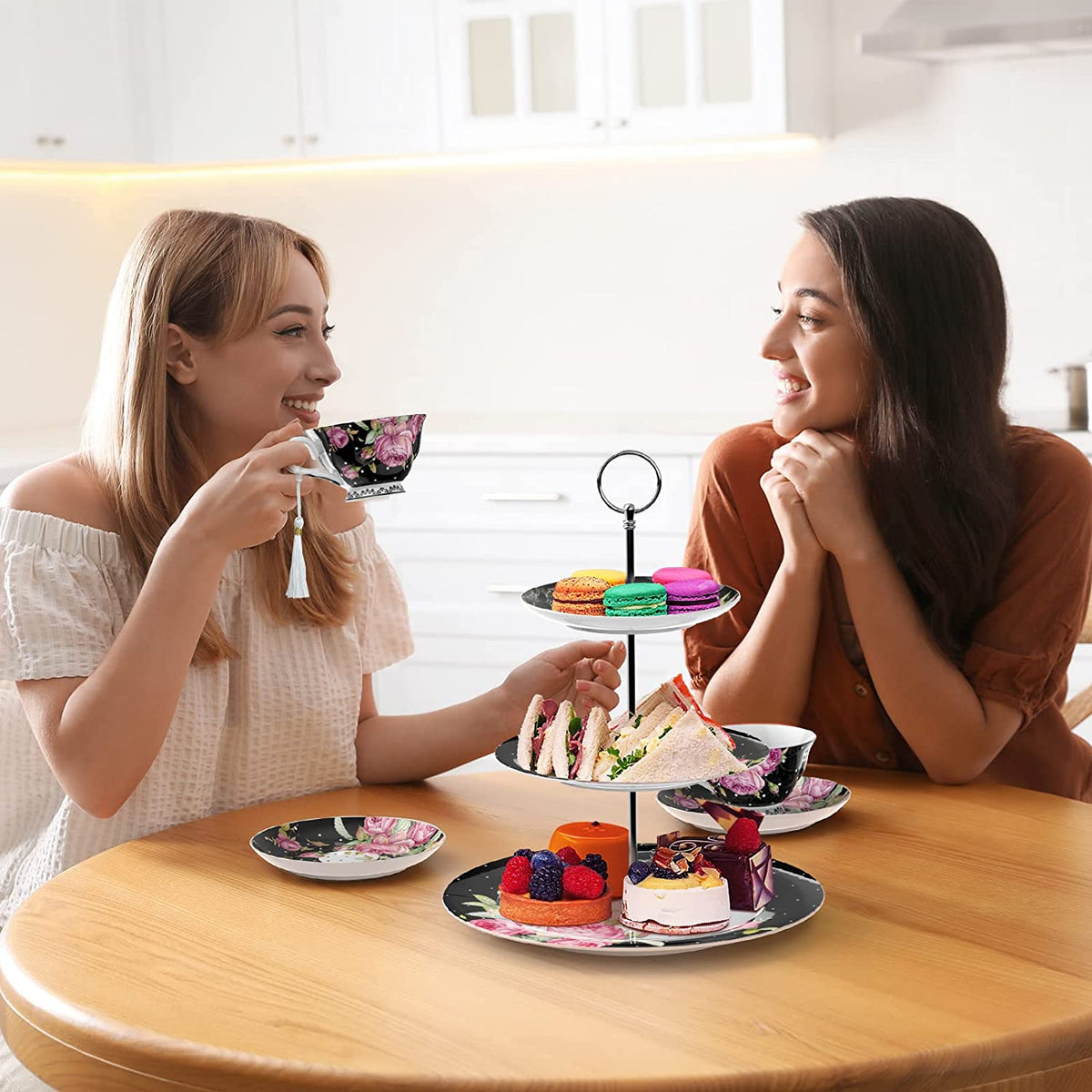 Elegant multi-tier cake stand with colourful desserts and tea cups in a stylish kitchen setting