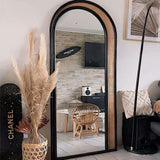 Elegant arched Nisu Home mirror with a black frame and natural rattan accents in a stylish interior