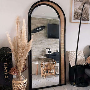 Elegant arched Nisu Home mirror with a black frame and natural rattan accents in a stylish interior