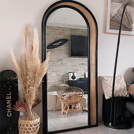 Elegant arched Nisu Home mirror with a black frame and natural rattan accents in a stylish interior