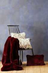 Orsina Fur Cushion in plush texture displayed on a chair with a burgundy throw blanket
