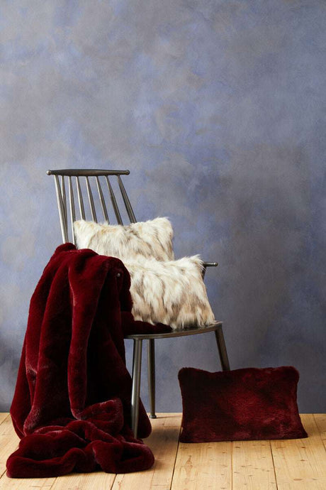Orsina Fur Cushion in plush texture displayed on a chair with a burgundy throw blanket