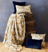 Orsina Fur Throw on a stack of woven baskets with matching cushions in navy blue