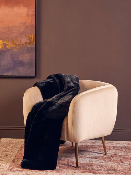 Orsina Black Fur Throw Draped Over a Stylish Cream Armchair in a Modern Living Room