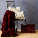 Orsina luxurious burgundy Fur Throw draped on a chair next to stylish decorative pillows