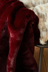Orsina Fur Throw in deep red, soft and luxurious, draped over a chair for added warmth and style