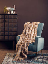 Orsina Fur Throw in luxurious brown tones draped over a stylish chair in a contemporary setting