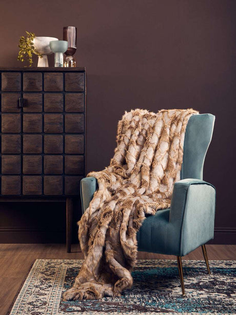 Orsina Fur Throw in luxurious brown tones draped over a stylish chair in a contemporary setting