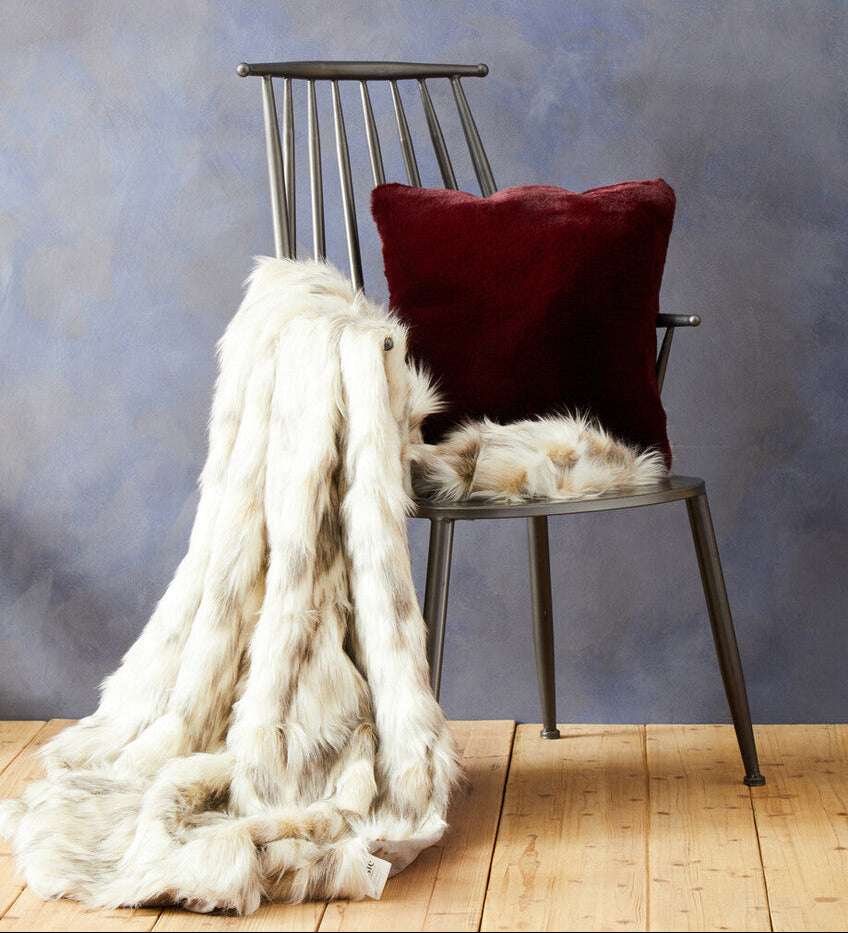 Orsina Fur Throw draped over a chair next to a plush cushion, perfect for cosy home decor