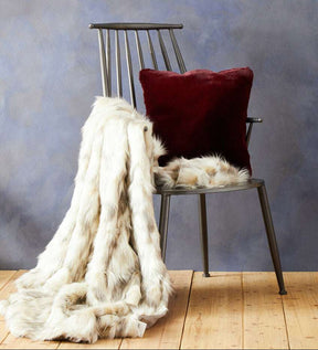 Orsina Fur Throw draped over a chair next to a plush cushion, perfect for cosy home decor