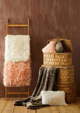 Orsina Fur Throw in soft textures displayed on a wooden ladder and woven baskets