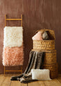 Orsina Fur Throw in soft textures displayed on a wooden ladder and woven baskets