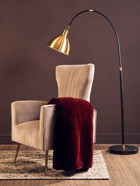 Luxurious burgundy Fur Throw draped over a stylish cream armchair in a modern living space
