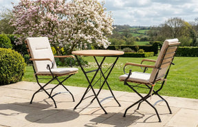 MINT Outdoor Garden Dining Set featuring a round table and two cushioned chairs in a scenic garden