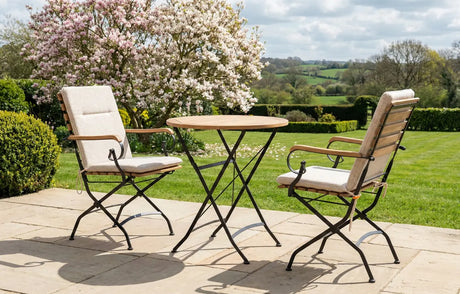 MINT Outdoor Garden Dining Set featuring a round table and two cushioned chairs in a scenic garden