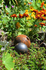 Decorative Garden Metal Balls nestled among vibrant flowers and greenery for outdoor beauty