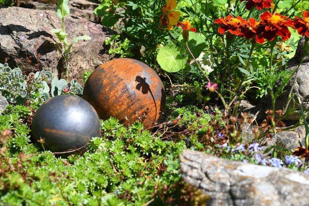 Rustic Garden Metal Balls nestled among vibrant flowers and greenery for garden decoration