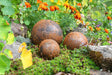 Rustic Garden Metal Balls in Various Sizes Surrounded by Colourful Flowers and Greenery