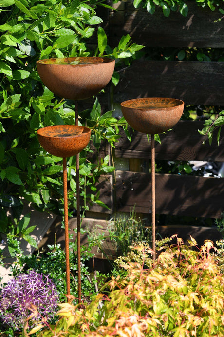 Three elegant rusty metal garden Rain Catcher bowls on tall stands for outdoor decor and rainwater collection