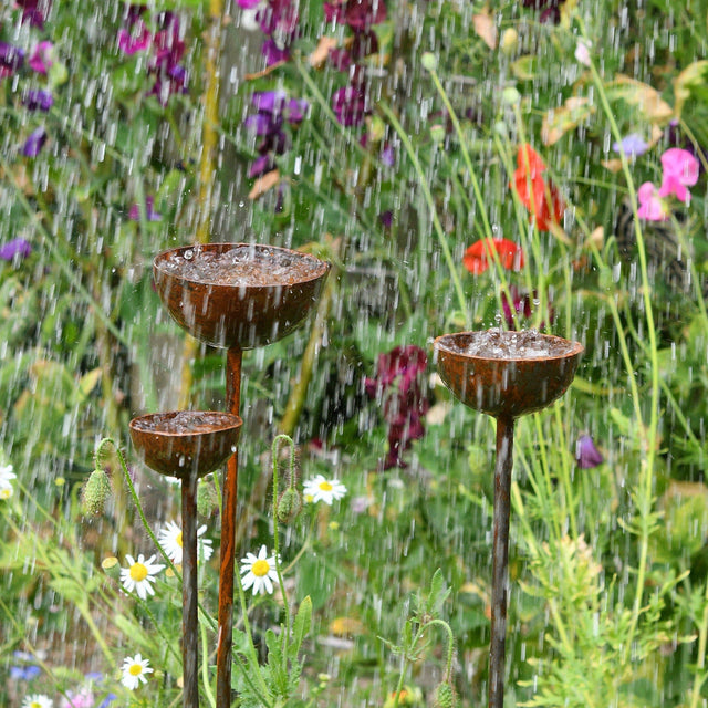 SavageWorksUK Rain Catcher in three tiers with water flowing, surrounded by vibrant flowers