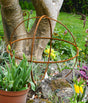 Rusty Garden Sphere Ornaments displayed in a vibrant garden with tulips and greenery