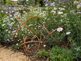 Decorative Garden Sphere Ornaments made of metal, nestled among vibrant flowers in a garden setting