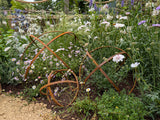 Decorative Garden Sphere Ornaments made of metal, nestled among vibrant flowers in a garden setting