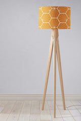 Stylish yellow geometric lampshade on a wooden tripod floor lamp for modern interiors