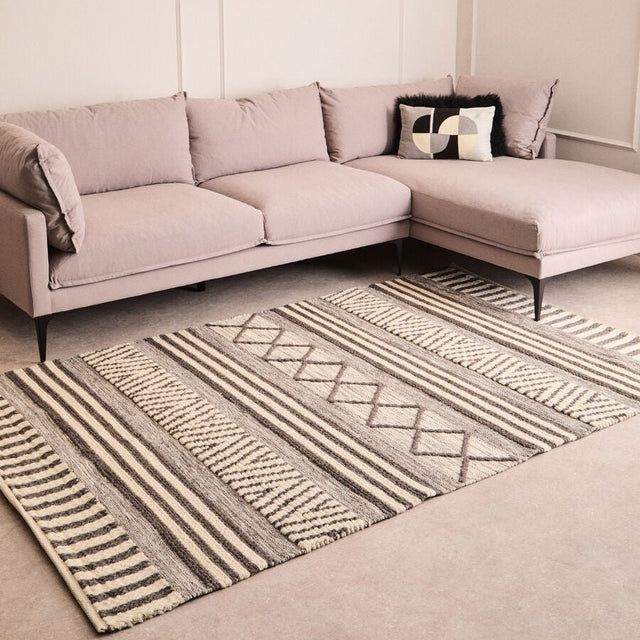 Orsina Geometric Rug in neutral tones placed under a modern sofa in a stylish living room