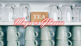 Collection of elegant glass mugs and ceramic cups displayed on a shelf for tea enthusiasts