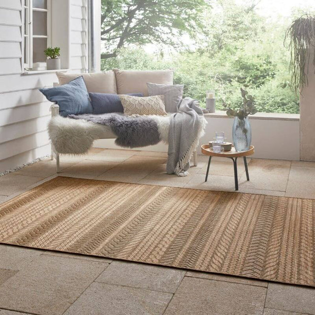 Granado Rug in natural tones placed on a patio with plush seating and decorative cushions