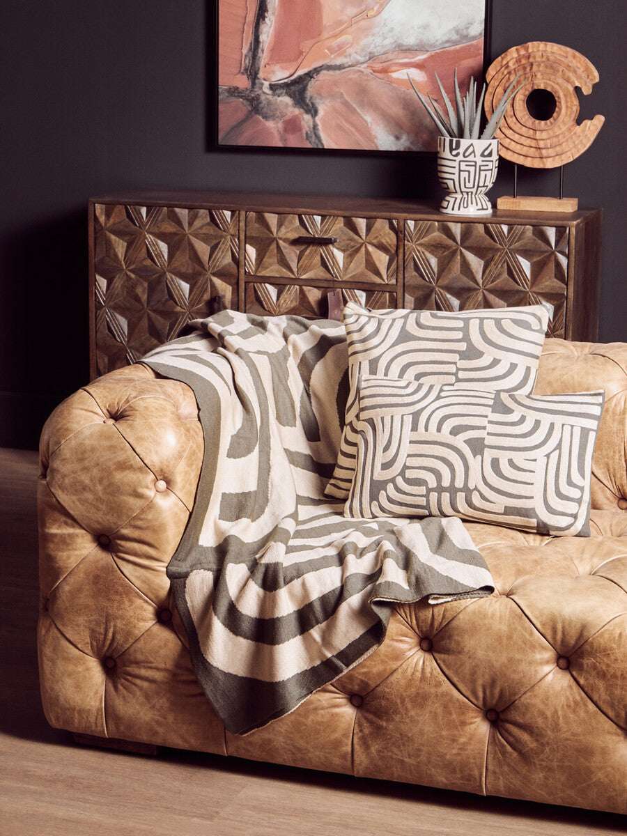 Orsina Green Throw draped over a vintage leather sofa, creating a stylish and cozy home decor