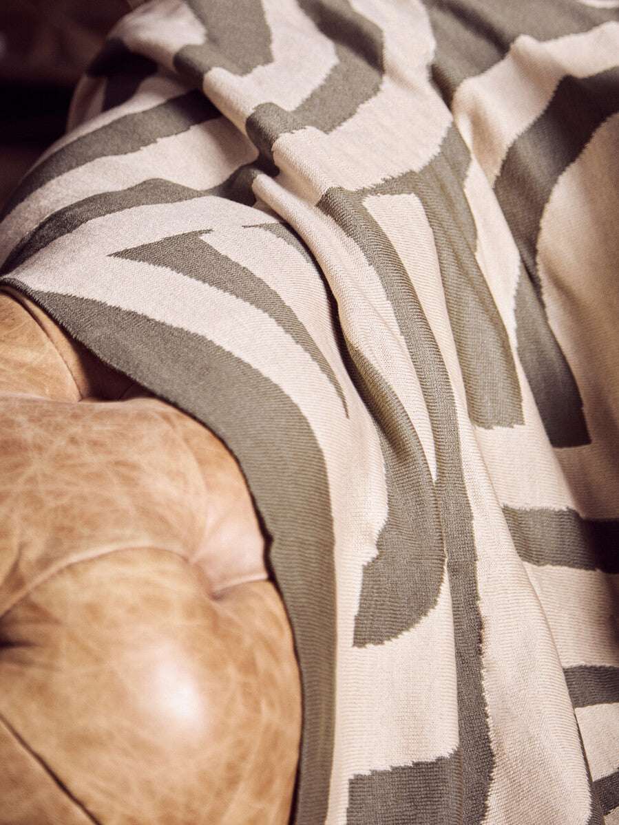 Stylish Orsina Green Throw with a contemporary pattern draped over a leather chair