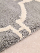 Close-up of an Orsina Hand Woven Rug in grey with cream geometric patterns