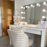 Hollywood Mirror with Bright LED Bulbs above a Stylish Vanity Table and Plush Chair