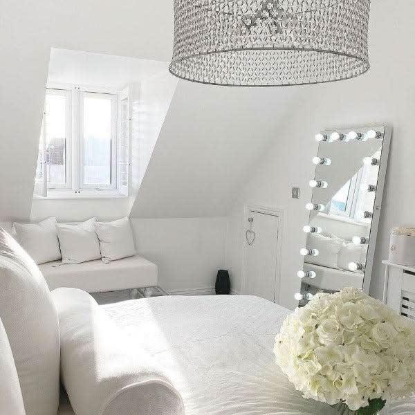 Stylish Hollywood Mirror in a bright bedroom with elegant decor and floral arrangements