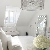 Stylish Hollywood Mirror in a bright bedroom with elegant decor and floral arrangements