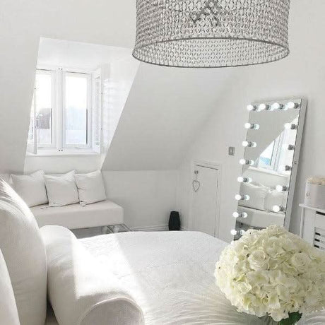 Stylish Hollywood Mirror in a bright bedroom with elegant decor and floral arrangements
