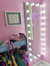 Elegant Hollywood Mirror with bright bulbs, reflecting a stylish pink room and clothes rack